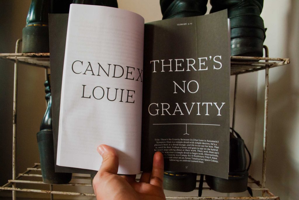 me holding the book open to a dramatic high contrast title page that says CANDEX LOUIE on the left and THERE'S NO GRAVITY on the right