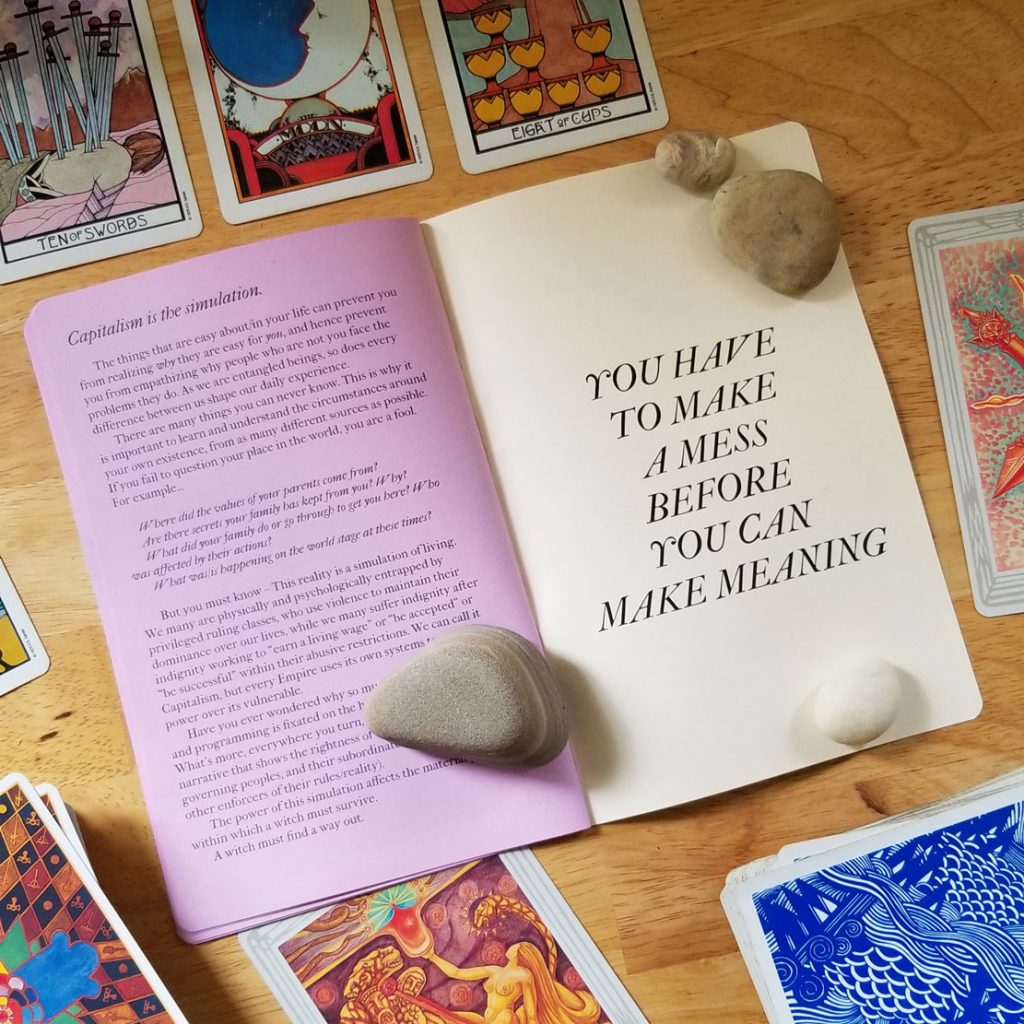 the zine on a desk, open to a back cover YOU HAVE TO MAKE A MESS BEFORE YOU MAKE MEANING, surrounded by tarot cards