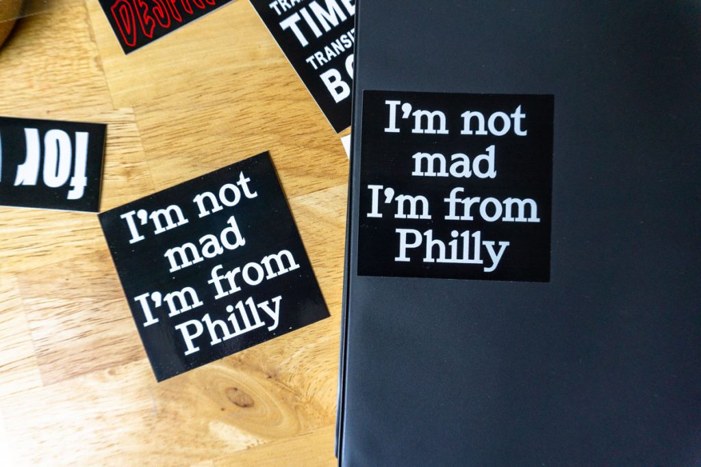 stickers on a wood table. they read "I'm not mad I'm from Philly"